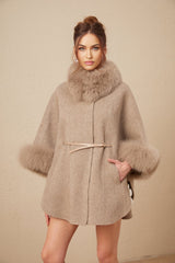 Woman wearing a brown wool cape coat with fur trim and belt cinched at waist