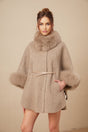 Woman wearing a brown wool cape coat with fur trim and belt cinched at waist