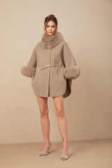 Woman wearing a brown wool cape coat with fur trim and belted waist