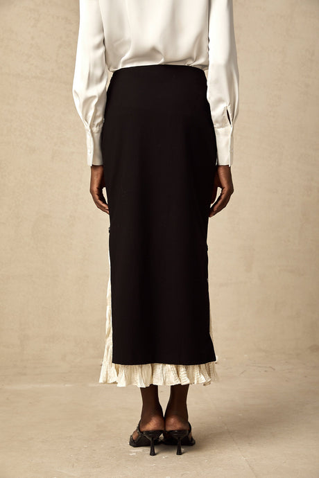 Woman wearing a colorblocked midi skirt with contrasting panels in different colors standing against a plain background