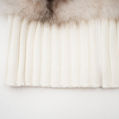 Woman wearing a cozy beige ribbed knit jacket with faux fur collar and cuffs standing against a plain background