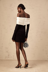 Woman wearing a fitted mini dress with color blocking and ruched details in contrasting colors