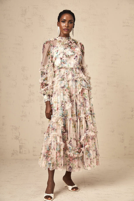 Woman wearing a floral patterned midi dress with ruffles and tulle fabric standing in a neutral background