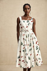 Woman wearing a floral print midi dress with a poplin fabric in light colors standing against a plain background
