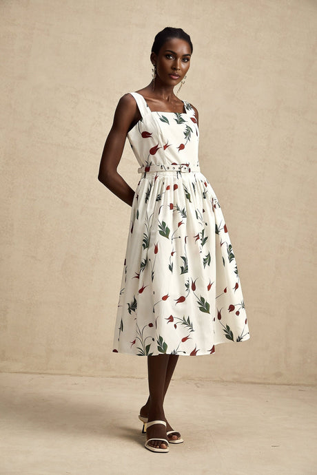 Woman wearing a floral print midi dress with poplin fabric and a vibrant pattern standing in a casual pose against a plain background