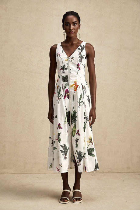 Woman wearing a floral print midi dress with vneck and poplin fabric in vibrant colors standing against a plain background