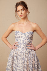 Woman wearing a floral print off shoulder midi dress with a fitted bodice and flowy skirt in a summer garden setting