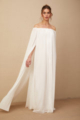 Woman wearing a flowing white tulle maxi dress with capelike design and draped details