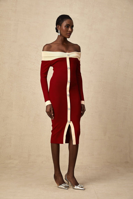 Woman wearing a formfitting offshoulder knit midi dress in a solid color standing against a plain background