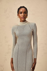 Woman wearing a gold ribbed knit midi dress with delicate pointelle detailing standing against a plain background