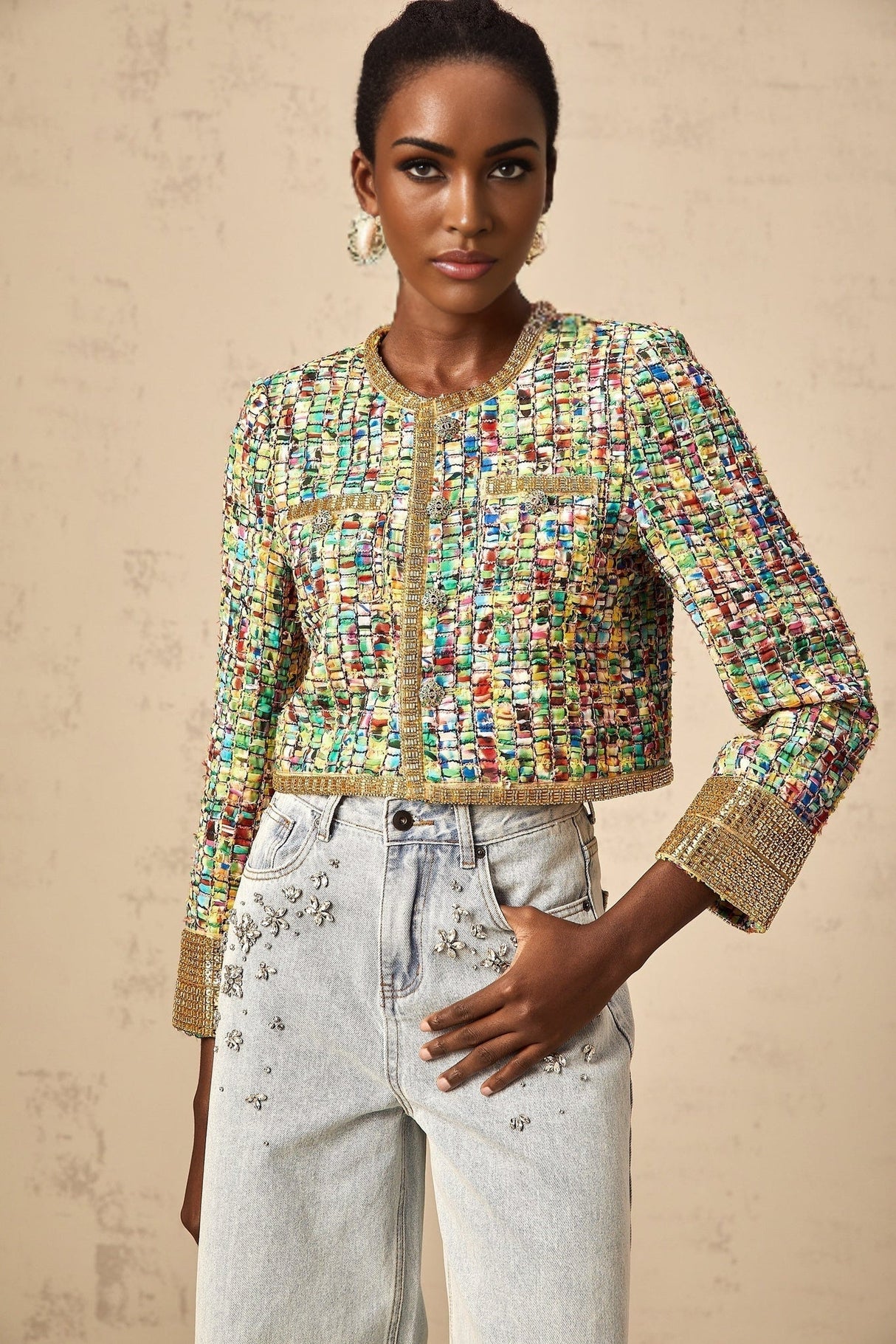 Woman wearing a gold sequined tweed jacket with a checkered pattern and gold tone buttons