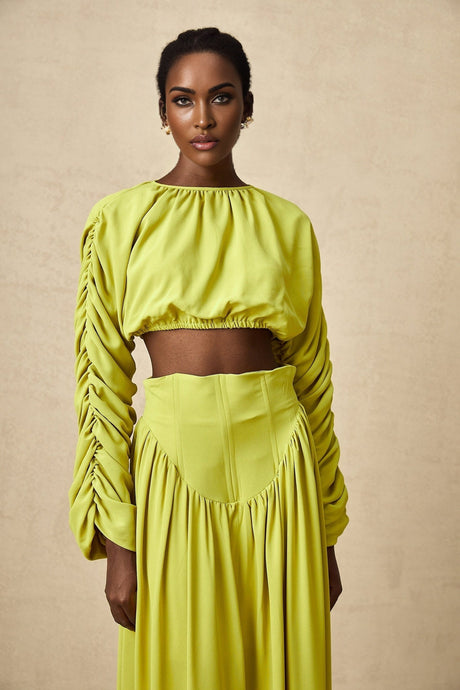 Woman wearing a green twopiece outfit consisting of a smocked top and matching skirt called Émilie
