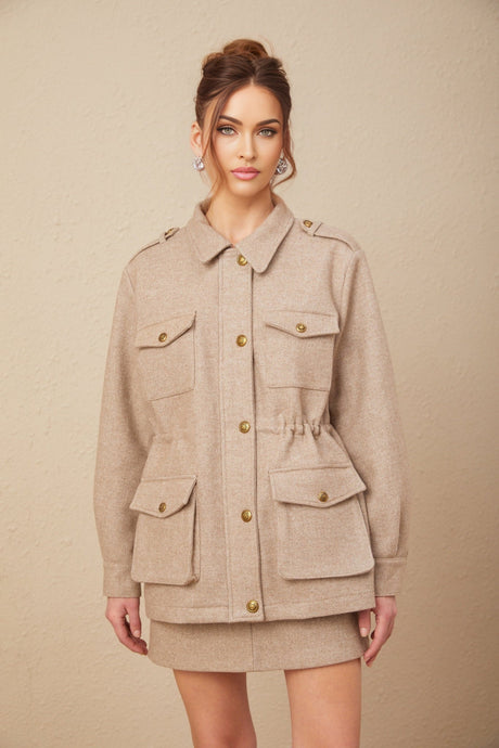 Woman wearing a khaki wool twill jacket with matching culottes standing against a plain background
