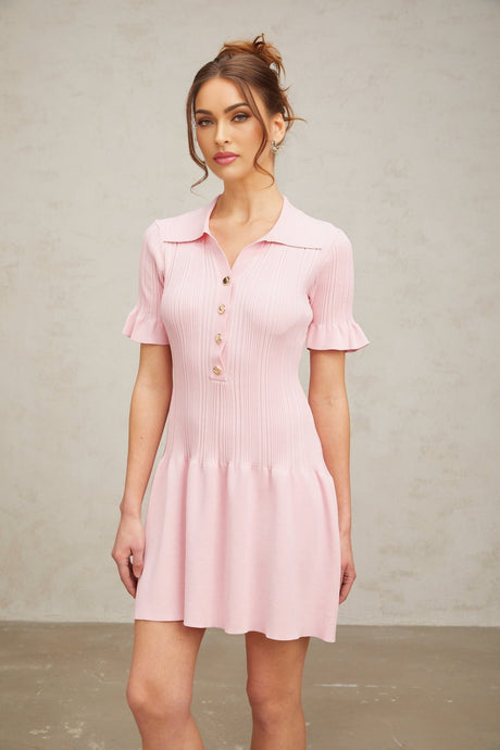 Woman wearing a light pink mini dress with a flared skirt and long sleeves made of fine knit fabric