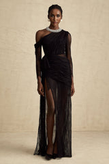 Woman wearing a long black dress with one shoulder strap and a cutout detail on the side