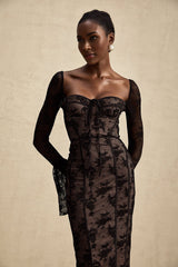 Woman wearing a long black flared maxi dress with lace details and long sleeves