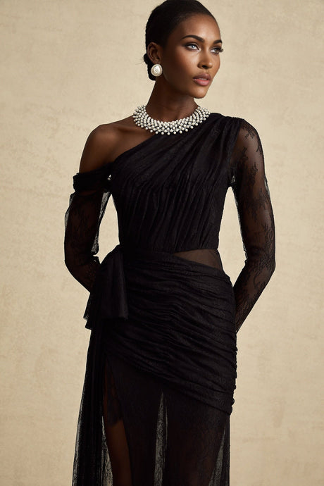 Woman wearing a long black maxi dress with one shoulder strap and cutout detail
