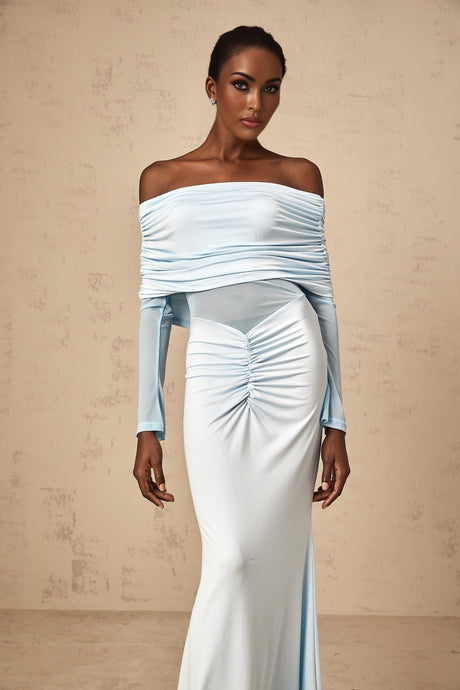 Woman wearing a long blue offshoulder dress with ruched details and flowing maxi length skirt