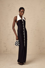 Woman wearing a long fitted maxi dress with colorblocked design in contrasting shades standing against a plain background