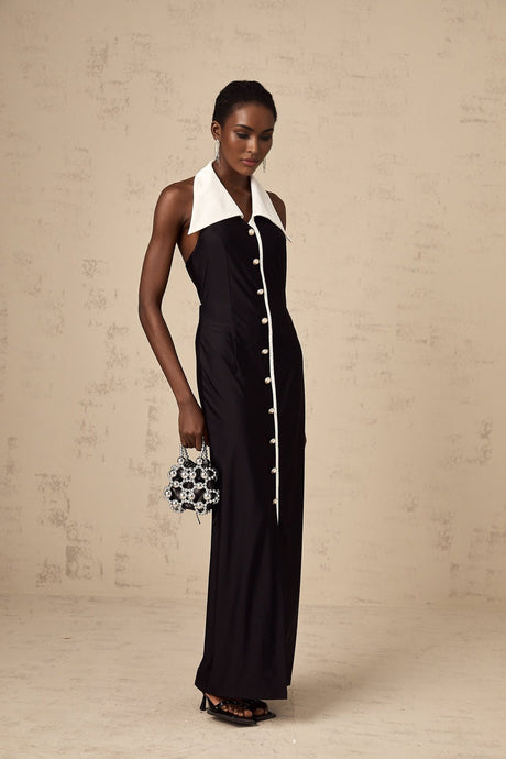 Woman wearing a long fitted maxi dress with colorblocked design in contrasting shades standing against a plain background