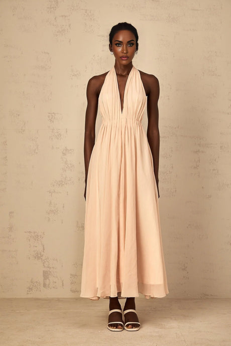 Woman wearing a long flowing halterneck maxi dress with shirred tulle fabric