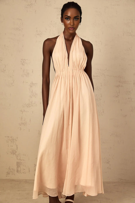 Woman wearing a long flowy halter neck maxi dress with shirred bodice and tulle skirt