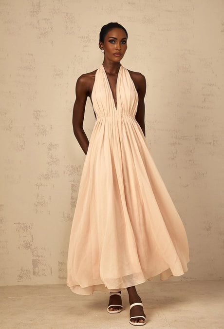 Woman wearing a long flowy halterneck maxi dress with shirred bodice and tulle skirt