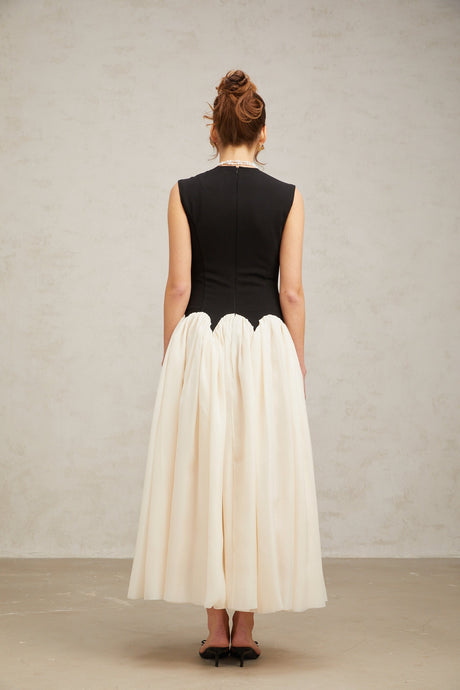 Woman wearing a long flowy maxi dress with puff sleeves and colorblocked design in contrasting colors