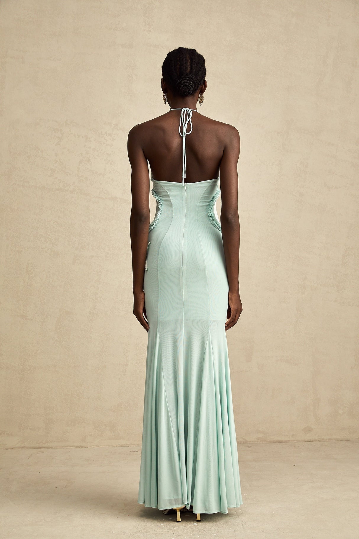 Woman wearing a long flowy maxi dress with ruffle details and butterfly pattern in pastel colors