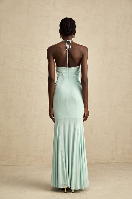 Woman wearing a long flowy maxi dress with ruffle details and butterfly pattern in pastel colors