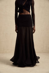 Woman wearing a long flowy maxi skirt with ruffles and pleats in a lightweight tulle fabric
