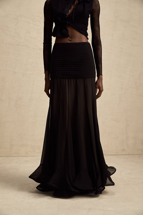 Woman wearing a long flowy maxi skirt with ruffles and pleats in a lightweight tulle fabric