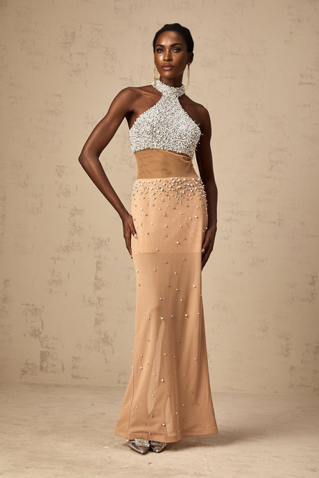 Woman wearing a long flowy white maxi dress with sheer fabric and pearl embellishments