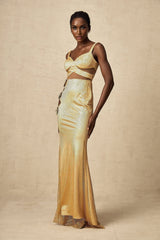 Woman wearing a long gold maxi dress with floral cutout pattern and flowing silhouette