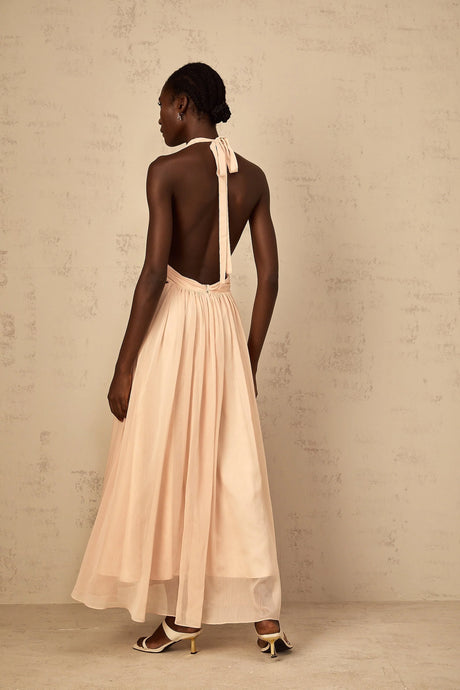 Woman wearing a long halterneck maxi dress with shirred bodice and flowing tulle skirt