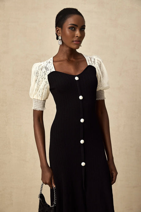 Woman wearing a long knit midi dress with lace trim details and a fitted silhouette in a neutral color