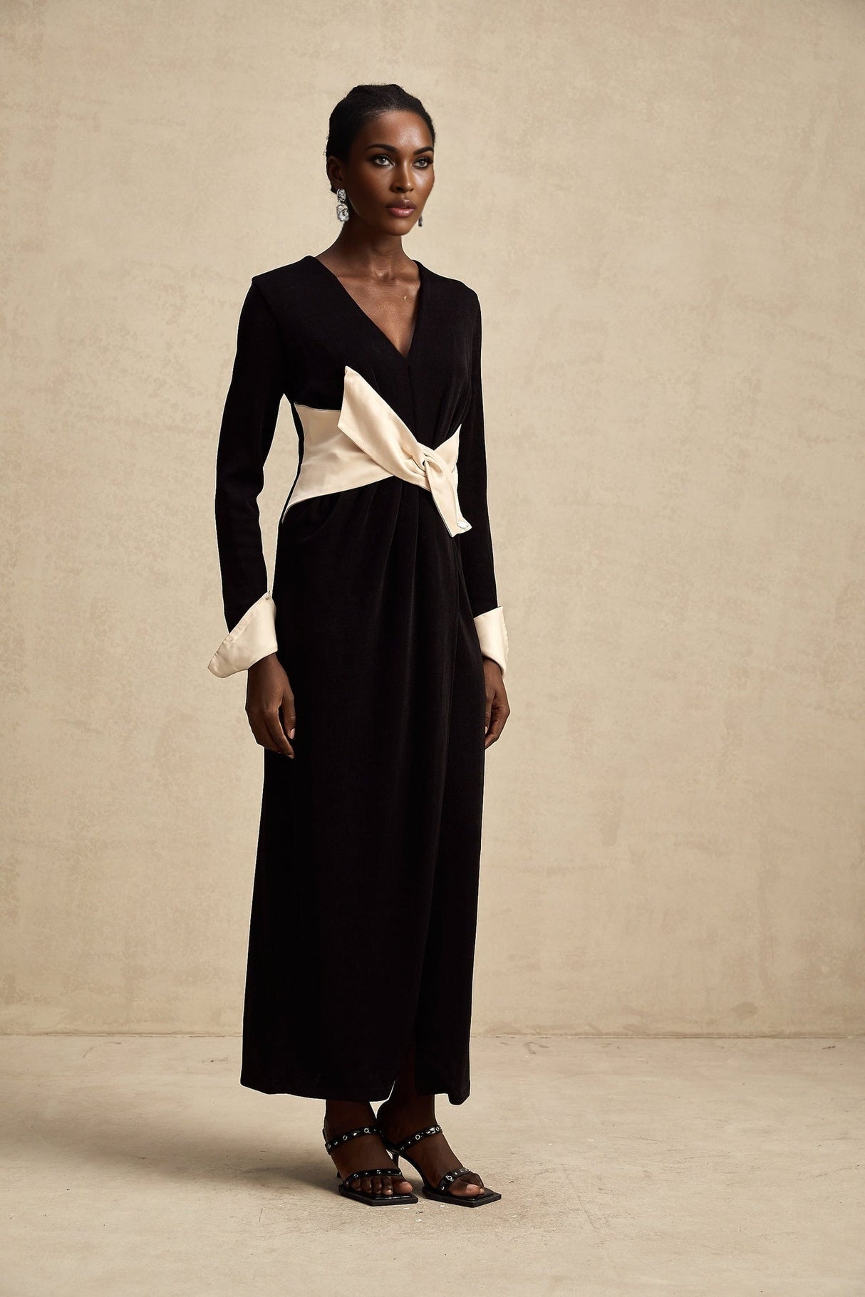 Woman wearing a long maxi dress with contrasting colors and a vneck design featuring a bowknot detail