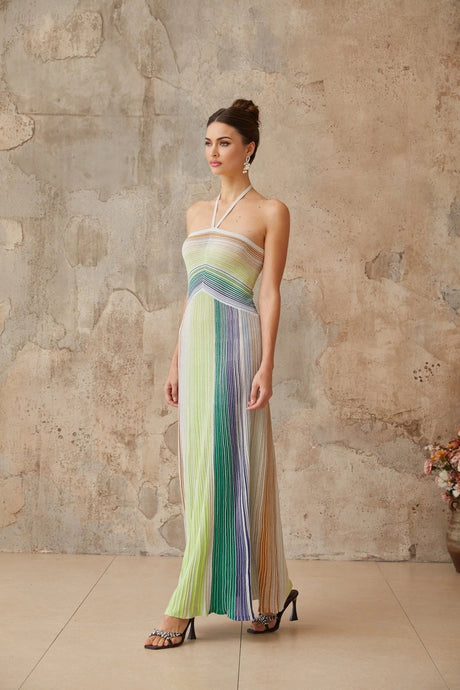 Woman wearing a long metallic knit maxi dress with a backless design standing in a relaxed pose