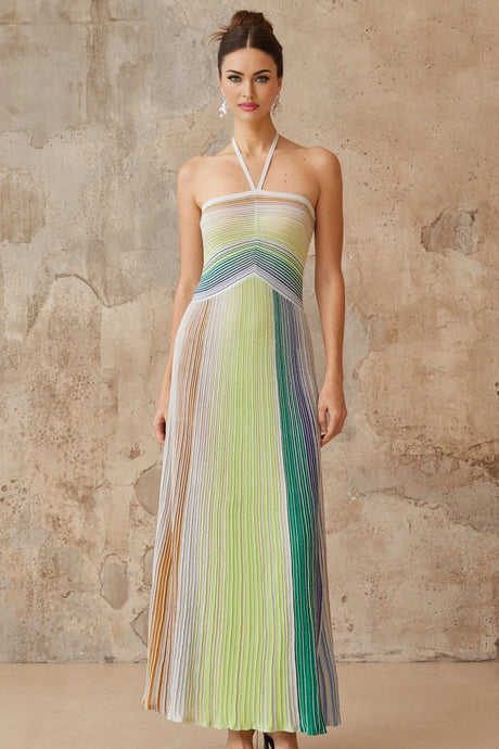 Woman wearing a long metallic knit maxi dress with backless design standing in elegant pose