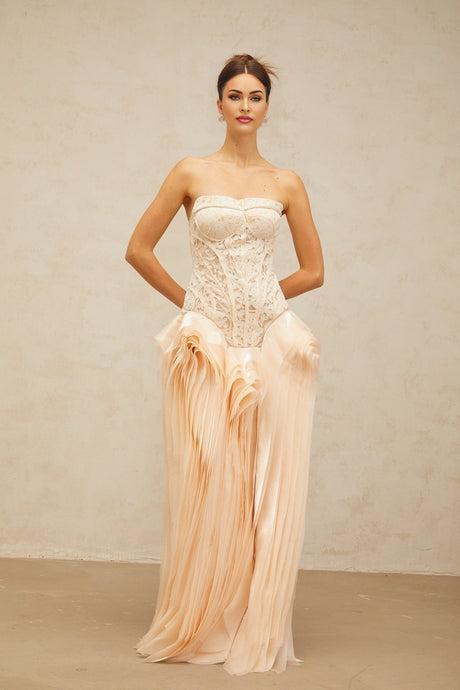 Woman wearing a long neutral colored lace corset maxi dress with layered details and delicate straps