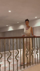 Woman wearing a long neutral colored maxi dress with floral lace panels and ribbon details