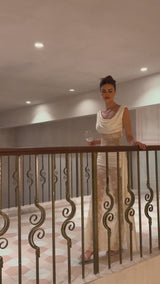 Woman wearing a long neutral colored maxi dress with floral lace panels and ribbon details
