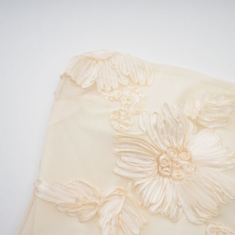 Woman wearing a long offshoulder maxi dress in neutral tones with embroidered details
