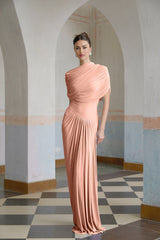 Woman wearing a long pink asymmetric pleated maxi dress with one shoulder strap