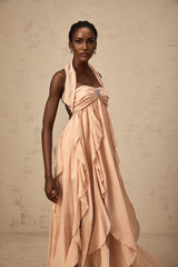 Woman wearing a long pink chiffon maxi dress with ruffle details and halter neck style