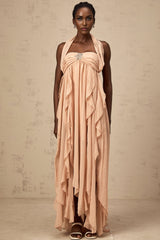 Woman wearing a long pink chiffon maxi dress with ruffles and halter neck style