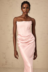 Woman wearing a long pink offshoulder maxi dress with flowing fabric standing in a relaxed pose