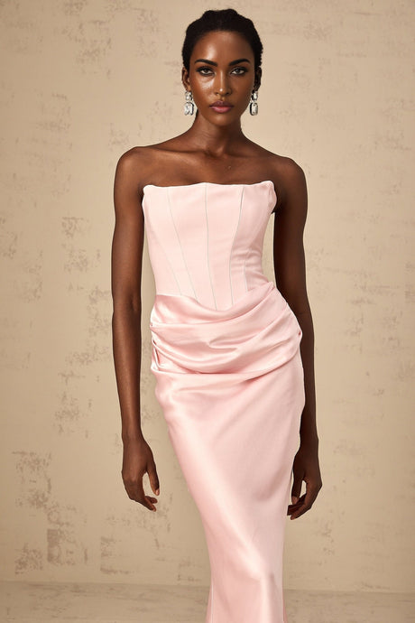Woman wearing a long pink offshoulder maxi dress with flowing fabric standing in a relaxed pose