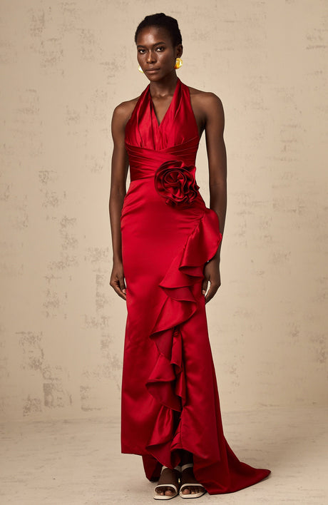 Woman wearing a long red halterneck maxi dress with ruffled 3D petal details