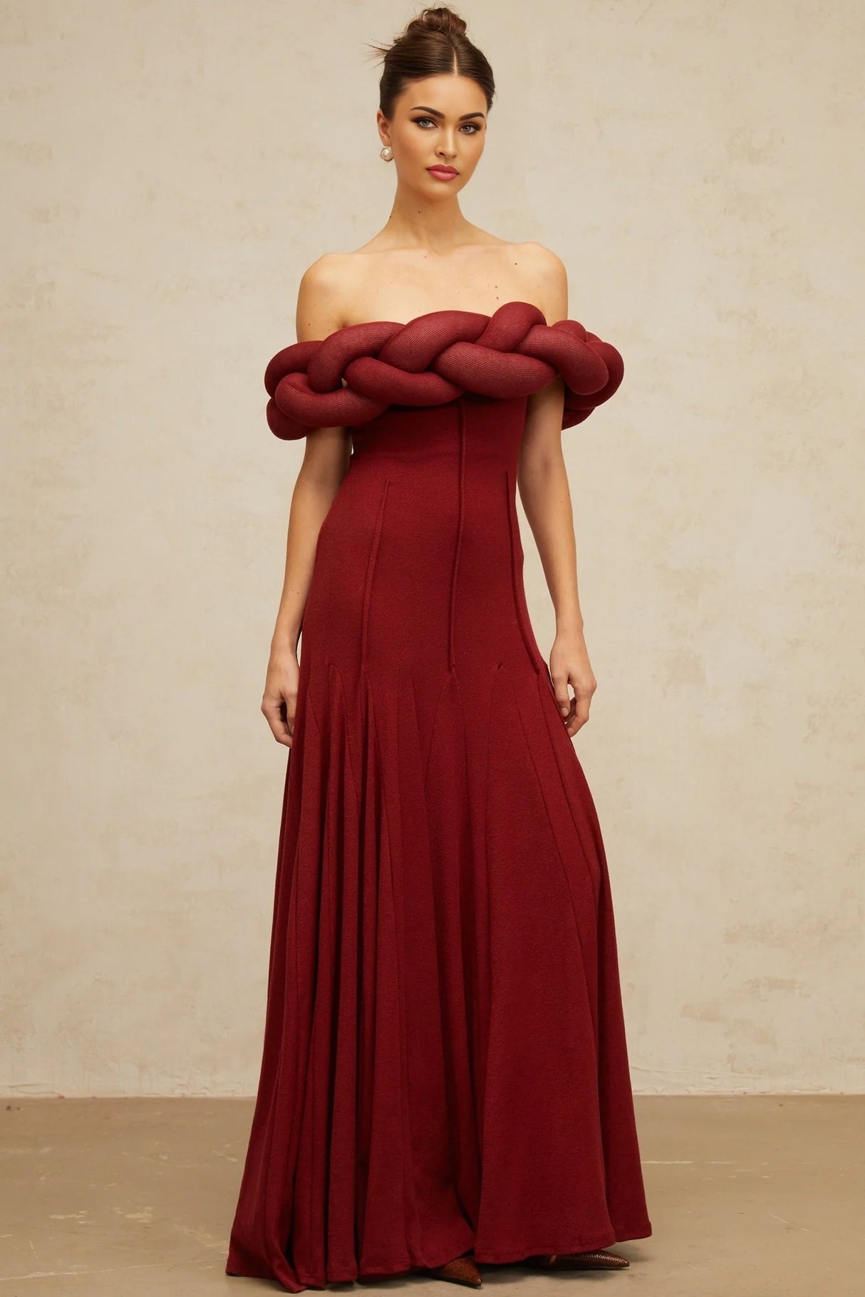 Woman wearing a long red knit maxi dress with braided design details